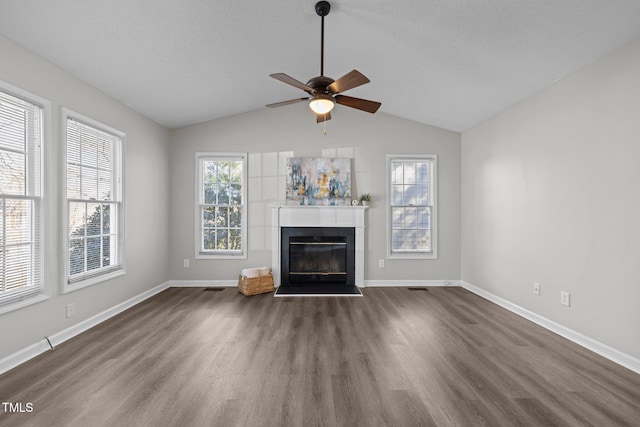 unfurnished living room with a tiled fireplace, lofted ceiling, dark wood-style floors, and baseboards