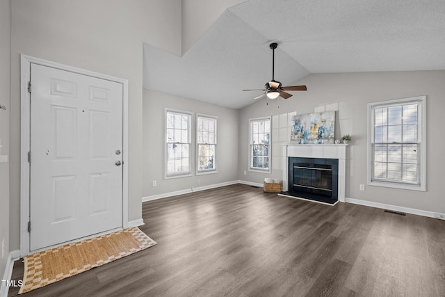 unfurnished living room featuring a ceiling fan, visible vents, lofted ceiling, dark wood-type flooring, and a glass covered fireplace