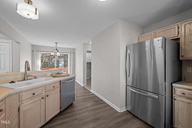 kitchen with light brown cabinets, dark wood-style flooring, a sink, light countertops, and appliances with stainless steel finishes