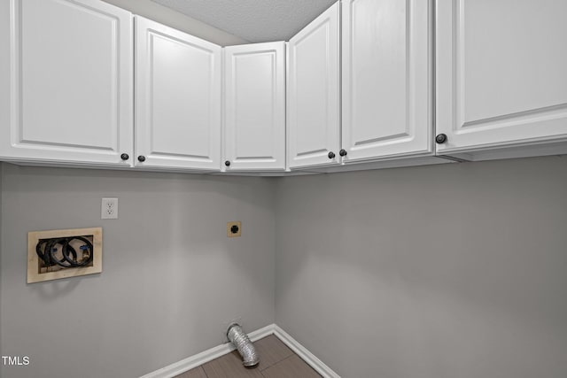 clothes washing area with cabinet space, hookup for an electric dryer, and baseboards