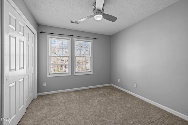 unfurnished bedroom featuring visible vents, a textured ceiling, baseboards, and carpet floors