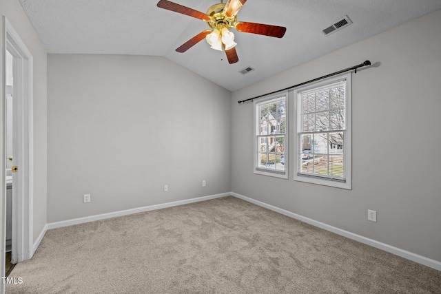 empty room featuring visible vents, lofted ceiling, baseboards, and carpet flooring