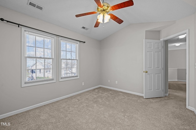 carpeted empty room featuring visible vents, baseboards, lofted ceiling, and a ceiling fan