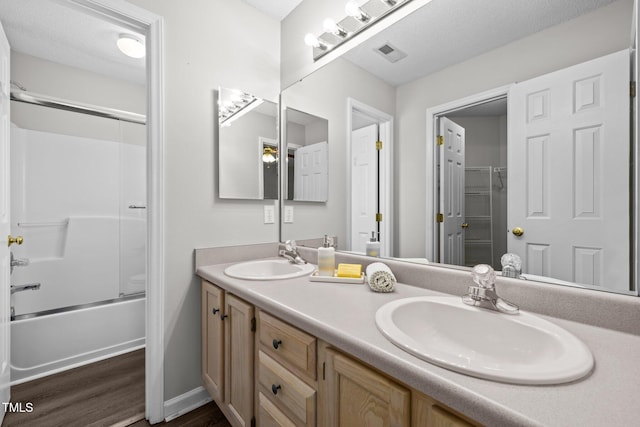 bathroom with double vanity, wood finished floors, visible vents, and a sink