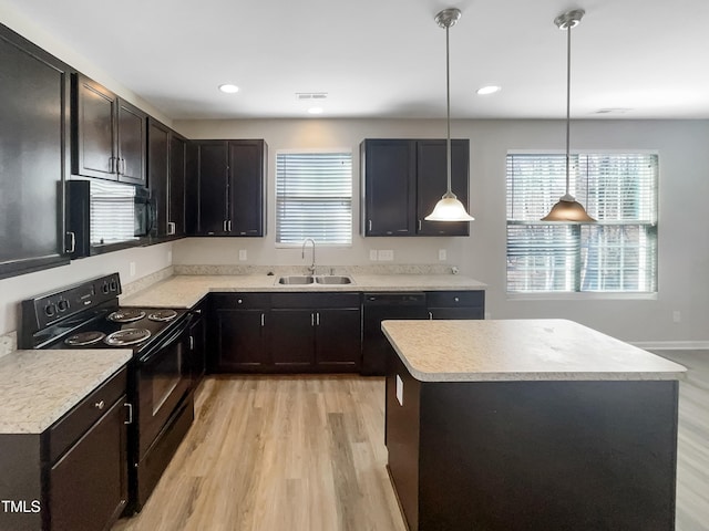 kitchen with black appliances, light countertops, light wood-type flooring, and a sink