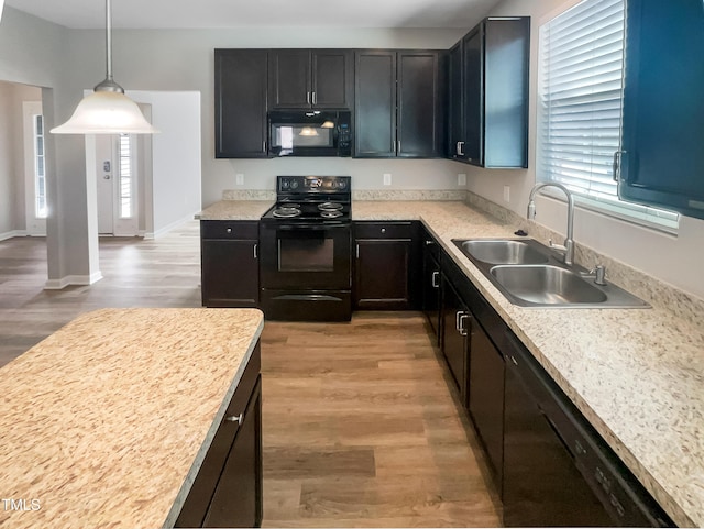kitchen featuring black appliances, light countertops, light wood-type flooring, and a sink