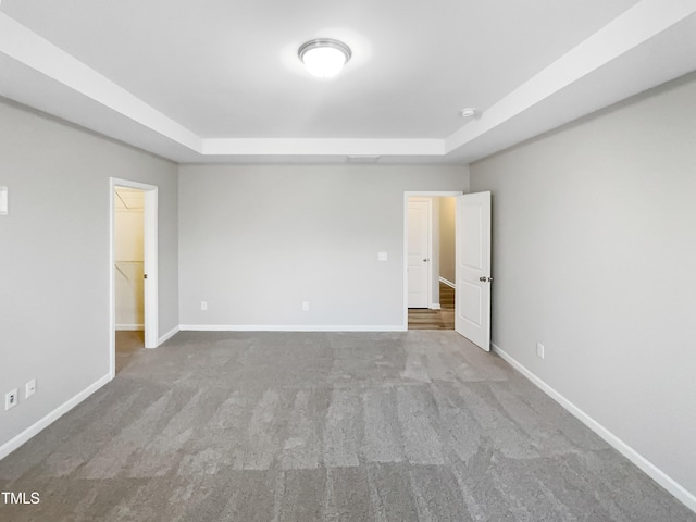 unfurnished bedroom with a tray ceiling, baseboards, and carpet floors