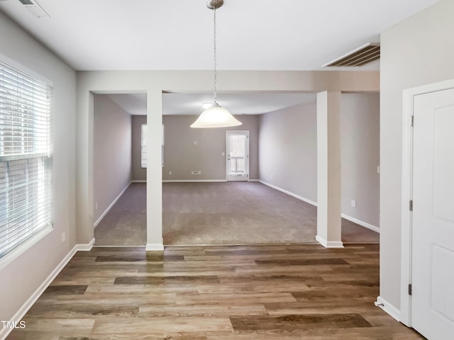 unfurnished dining area featuring wood finished floors, baseboards, and visible vents