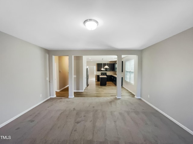 unfurnished living room with light colored carpet and baseboards