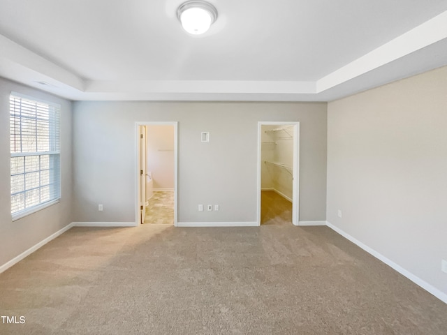 empty room with a tray ceiling, baseboards, and carpet floors