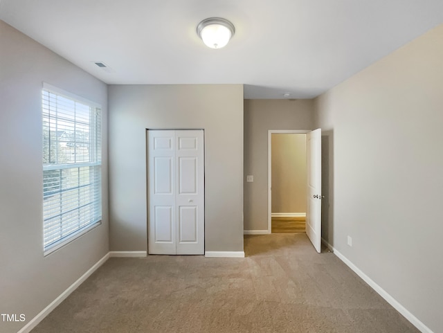 unfurnished bedroom with a closet, baseboards, visible vents, and carpet floors