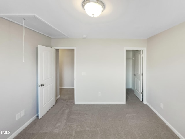 unfurnished bedroom with baseboards, a closet, carpet floors, and attic access