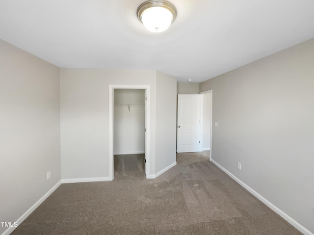 unfurnished bedroom with a walk in closet, carpet, baseboards, and a closet