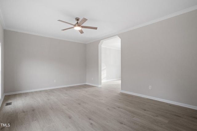 spare room featuring visible vents, a ceiling fan, wood finished floors, arched walkways, and baseboards