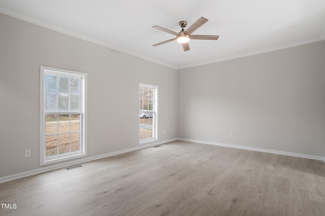 spare room with light wood finished floors, visible vents, baseboards, and ornamental molding