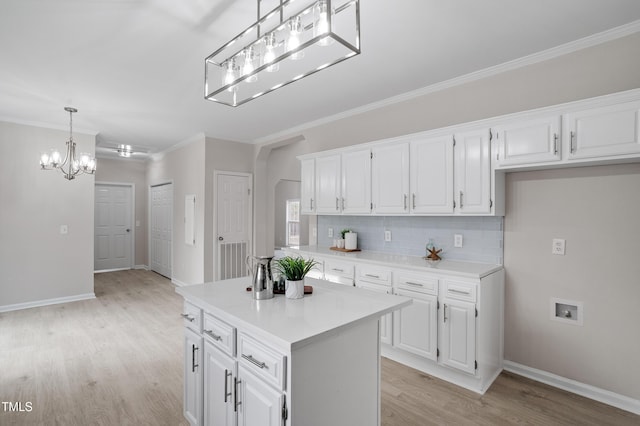 kitchen with backsplash, light wood-style floors, white cabinets, light countertops, and a chandelier