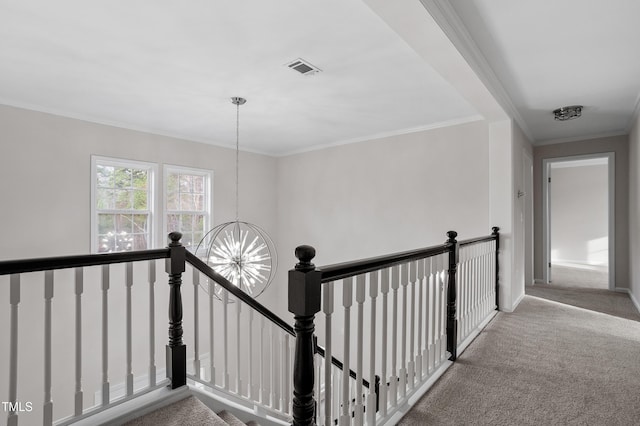 corridor featuring a notable chandelier, crown molding, carpet flooring, and an upstairs landing