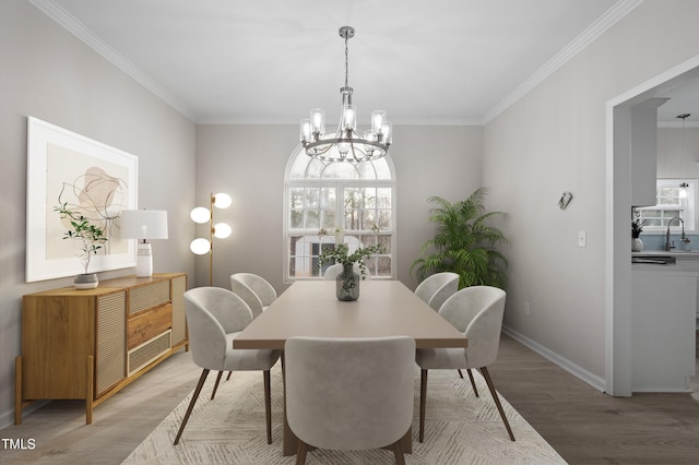 dining area with a chandelier, crown molding, and light wood-style floors