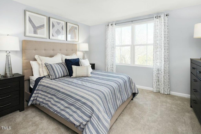 bedroom with baseboards and light colored carpet