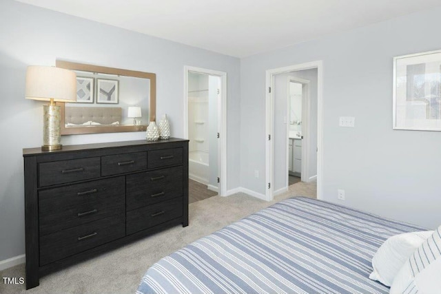 bedroom with baseboards, light carpet, and ensuite bath