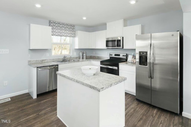 kitchen with dark wood finished floors, a kitchen island, stainless steel appliances, and a sink