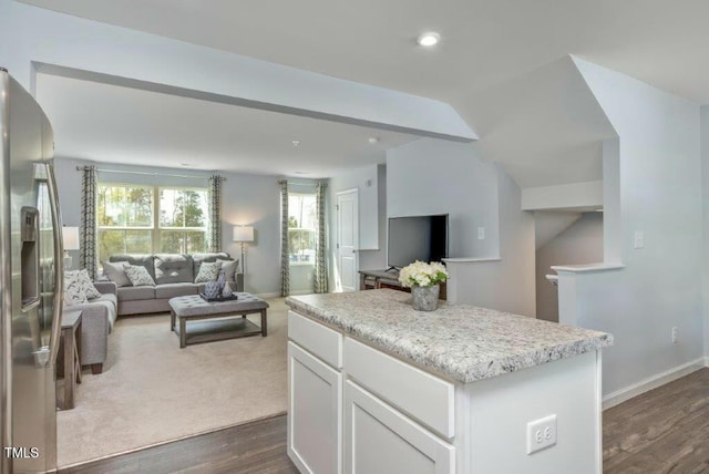 kitchen with dark wood finished floors, a center island, open floor plan, stainless steel fridge, and white cabinets