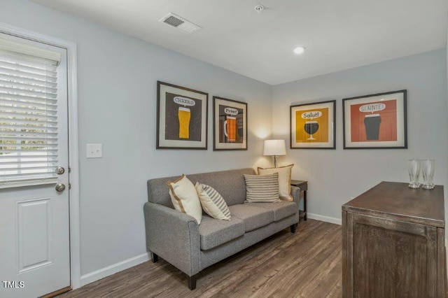 living room with wood finished floors, visible vents, and baseboards