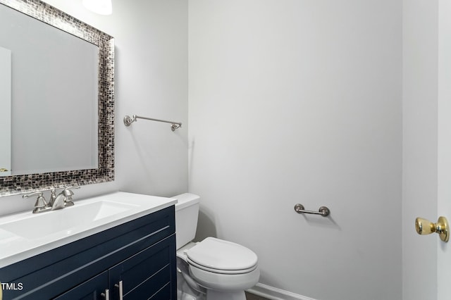 half bath with vanity, toilet, and baseboards