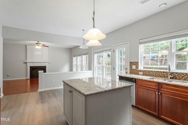 kitchen with a fireplace, a sink, light wood-style floors, dishwasher, and backsplash