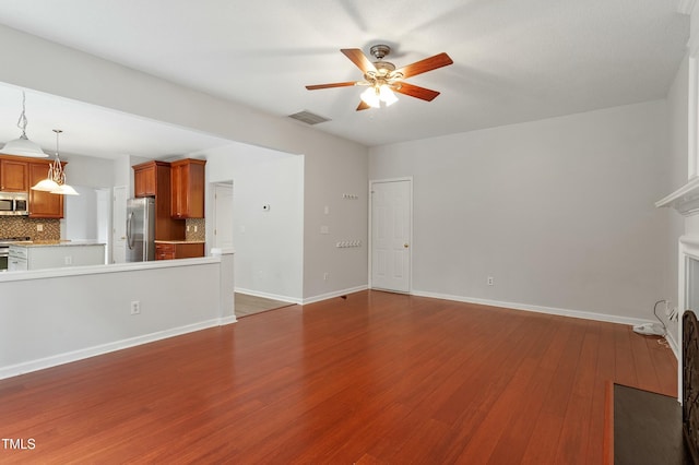 unfurnished living room featuring visible vents, baseboards, dark wood finished floors, a fireplace, and a ceiling fan