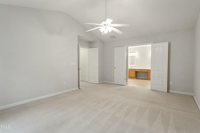 unfurnished bedroom featuring baseboards, visible vents, lofted ceiling, ensuite bathroom, and light colored carpet