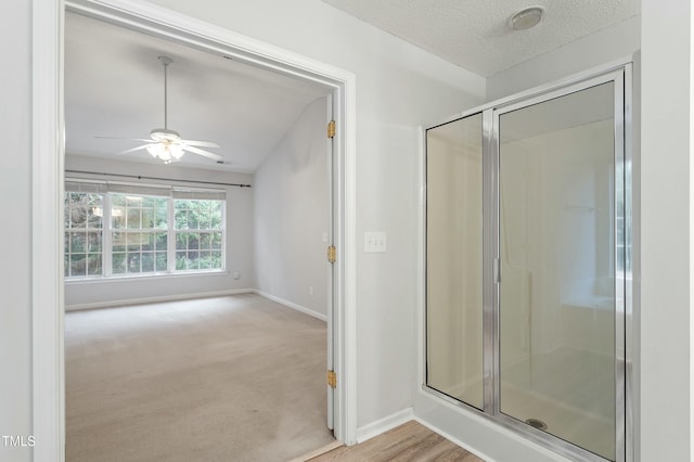 bathroom with ceiling fan, a stall shower, a textured ceiling, and baseboards