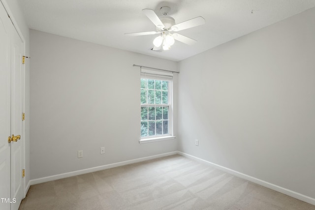 spare room with baseboards, light carpet, and a ceiling fan