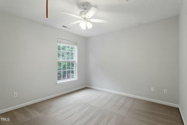 unfurnished room featuring carpet flooring, baseboards, visible vents, and ceiling fan