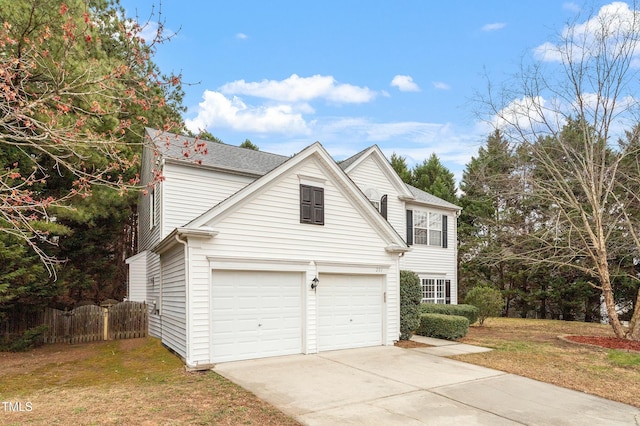 view of front facade with concrete driveway, a front lawn, and fence