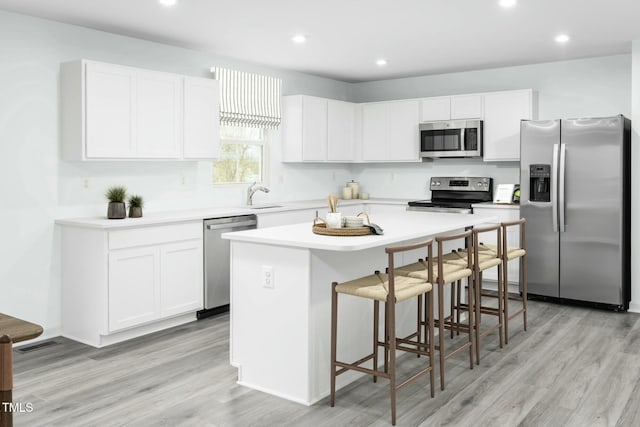 kitchen featuring a sink, a kitchen island, white cabinetry, and stainless steel appliances