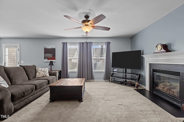 living area featuring a fireplace with flush hearth, carpet, baseboards, and ceiling fan