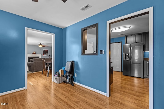 hallway with light wood-style flooring, baseboards, and visible vents