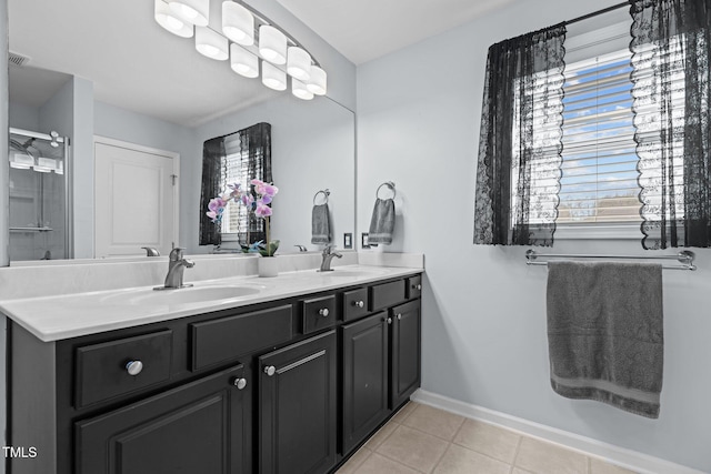 full bath featuring tile patterned flooring, double vanity, baseboards, and a sink