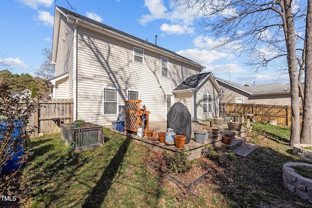 rear view of property with a yard, a vegetable garden, and fence