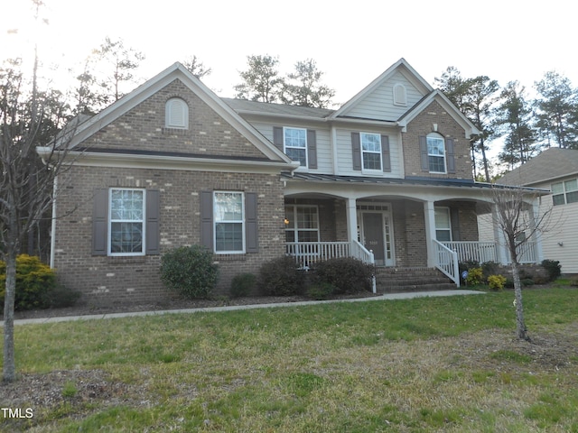 view of front of property featuring brick siding, a porch, a standing seam roof, and a front lawn