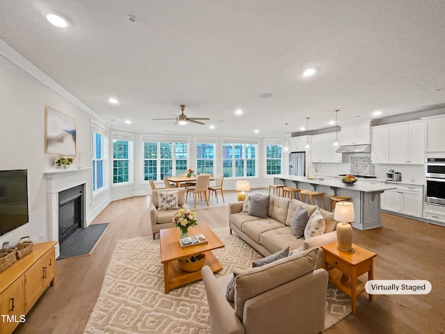 living area featuring light wood finished floors, recessed lighting, and a premium fireplace