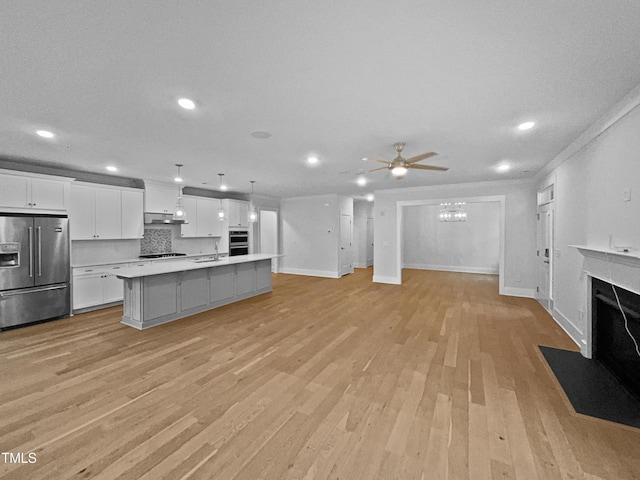 kitchen featuring a fireplace with flush hearth, under cabinet range hood, white cabinetry, high quality fridge, and open floor plan