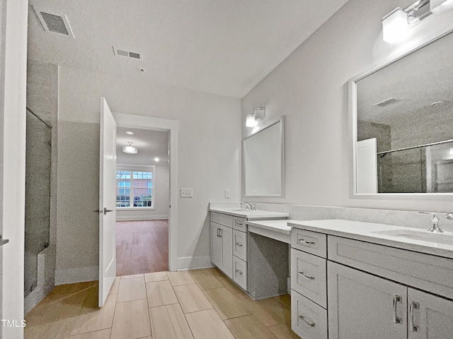 full bath with a sink, visible vents, two vanities, and a shower stall