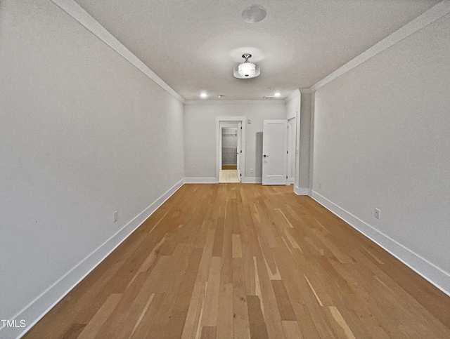 empty room with wood finished floors, baseboards, and ornamental molding