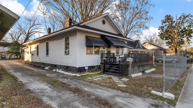 view of front facade with crawl space, a wooden deck, a chimney, and fence