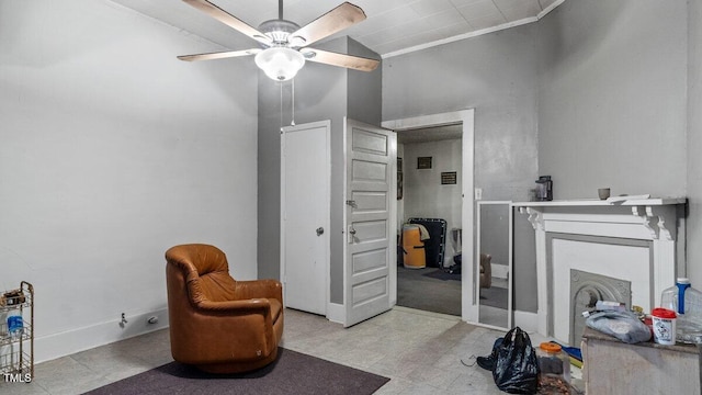 sitting room with tile patterned floors, baseboards, a ceiling fan, and crown molding