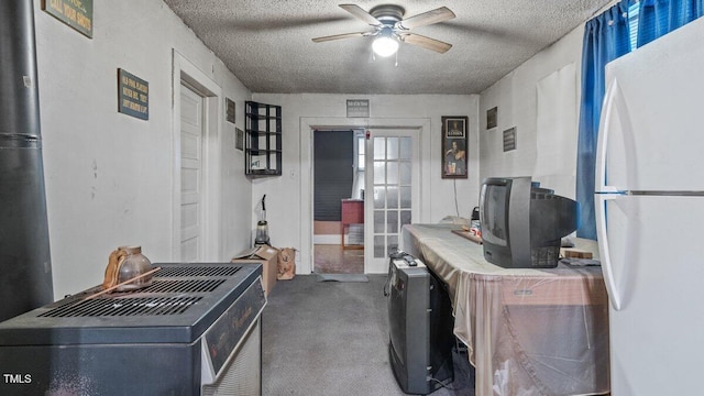 carpeted home office featuring a textured ceiling and ceiling fan