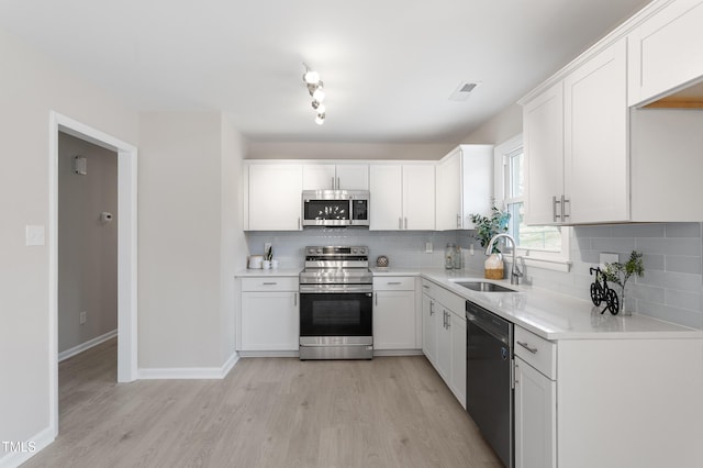 kitchen featuring visible vents, a sink, appliances with stainless steel finishes, white cabinetry, and light wood-type flooring