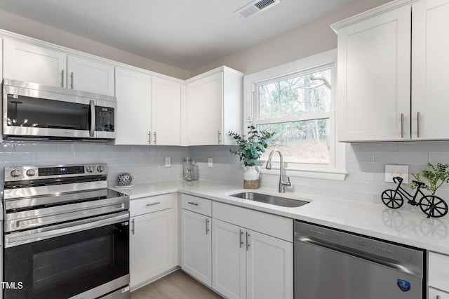 kitchen with tasteful backsplash, visible vents, light countertops, appliances with stainless steel finishes, and a sink